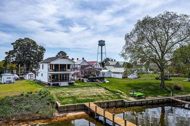 rear view of property with a lawn, a water view, and a balcony