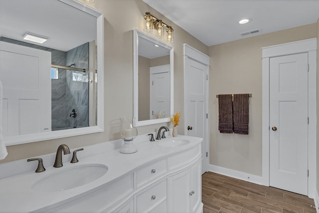 full bath featuring visible vents, a sink, double vanity, and a shower stall
