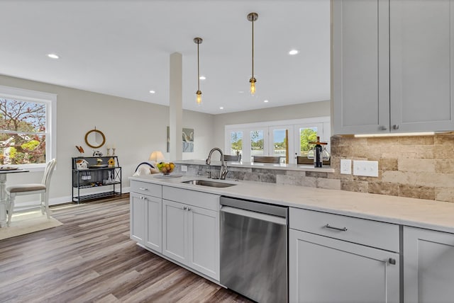 kitchen featuring decorative backsplash, dishwasher, a sink, light wood-style floors, and recessed lighting