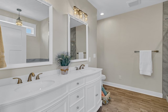 bathroom featuring baseboards, visible vents, a sink, and wood finished floors