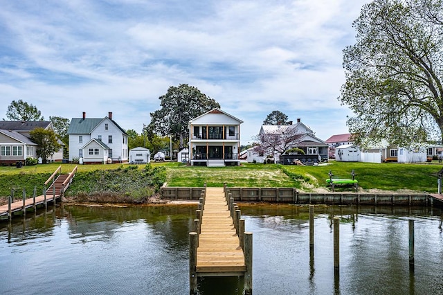 view of dock with a residential view, a water view, and a yard