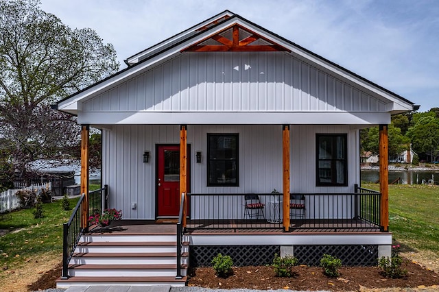bungalow-style home with covered porch, a water view, and a front yard