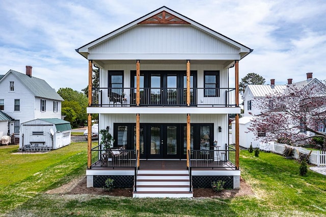 back of property featuring a lawn, an outbuilding, french doors, and a balcony