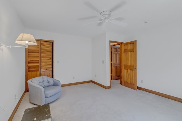 living area featuring light carpet and ceiling fan