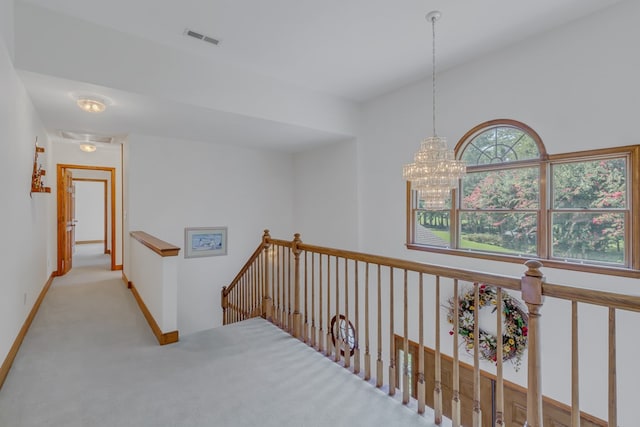 corridor with a chandelier and light colored carpet