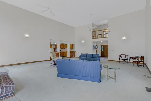 carpeted living room featuring ceiling fan and a towering ceiling