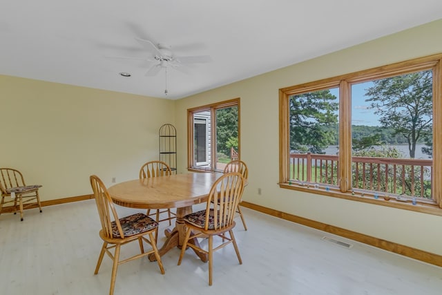 dining room featuring ceiling fan, a water view, and light wood-type flooring