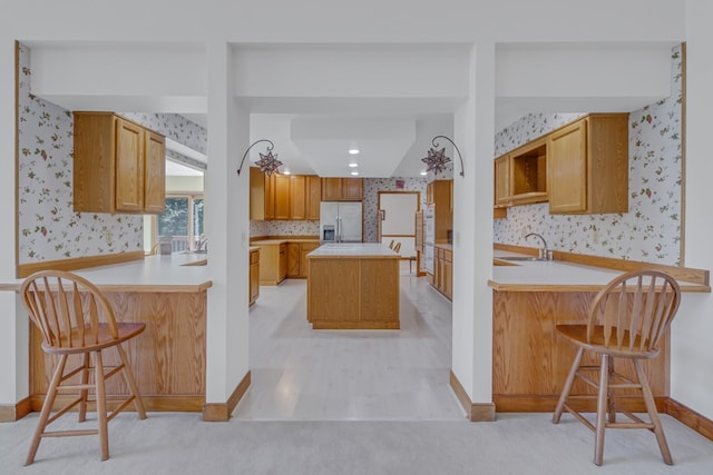 kitchen featuring a kitchen bar, kitchen peninsula, and stainless steel refrigerator with ice dispenser