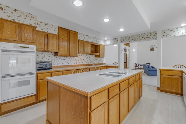 kitchen with a center island with sink, light hardwood / wood-style floors, white appliances, and sink