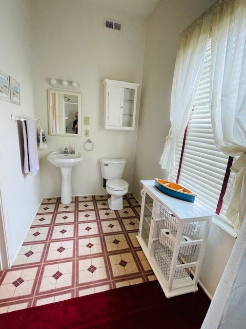 bathroom with toilet, a healthy amount of sunlight, and visible vents