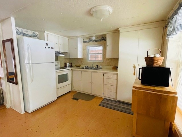 kitchen featuring light wood-style flooring, a sink, under cabinet range hood, white appliances, and light countertops