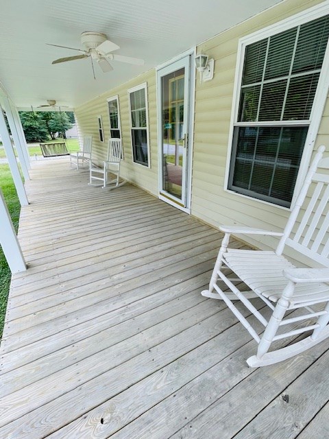 wooden terrace with a ceiling fan and covered porch