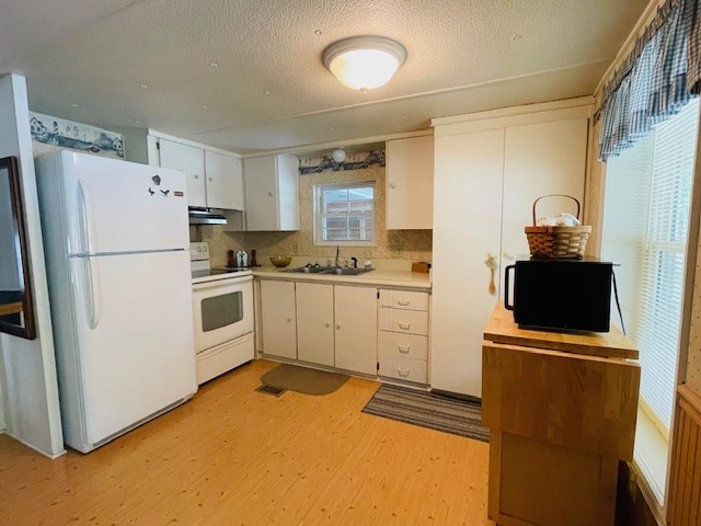 kitchen with white appliances, a sink, light countertops, light wood-style floors, and under cabinet range hood