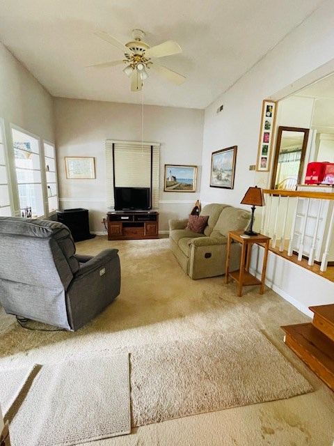 carpeted living room featuring baseboards and a ceiling fan