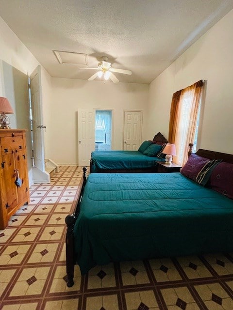 bedroom featuring light floors, a textured ceiling, attic access, and a ceiling fan