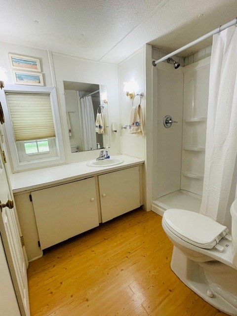 full bathroom with vanity, a shower with shower curtain, wood finished floors, a textured ceiling, and toilet