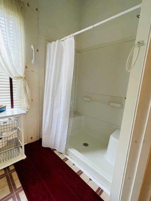 full bathroom featuring tile patterned floors and a shower stall