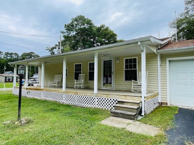 view of front of home with a porch, a garage, a front yard, and aphalt driveway