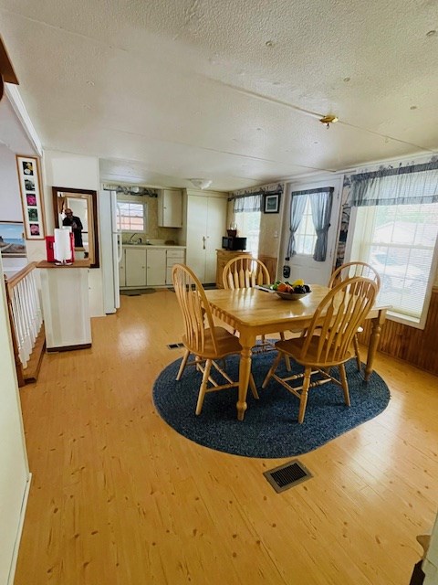 dining area with visible vents, a healthy amount of sunlight, a textured ceiling, and light wood-style floors