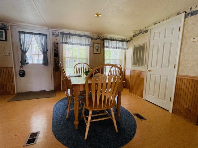 dining space featuring plenty of natural light, visible vents, and wainscoting