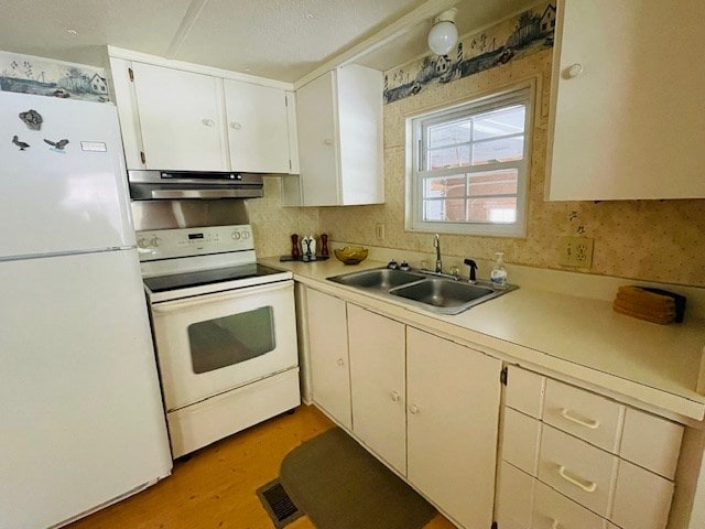 kitchen featuring under cabinet range hood, white appliances, light countertops, and a sink