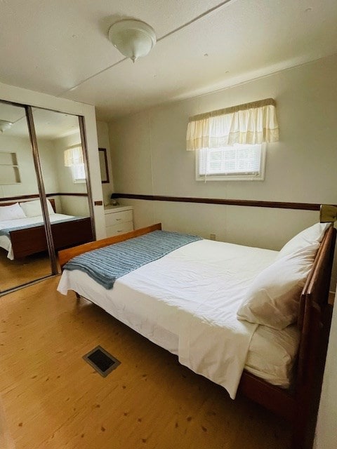 bedroom featuring a closet, visible vents, and wood finished floors