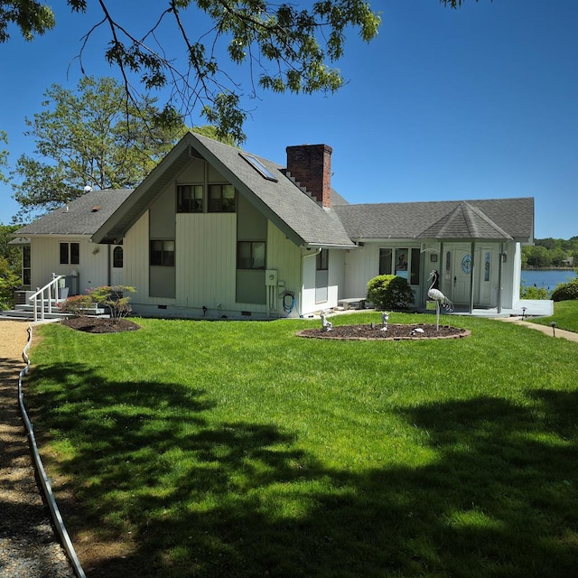 back of property with a yard, roof with shingles, solar panels, and a chimney