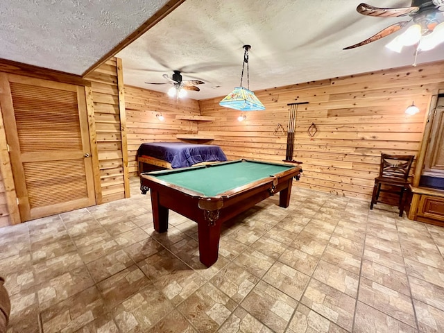 recreation room featuring a textured ceiling, ceiling fan, wooden walls, and billiards