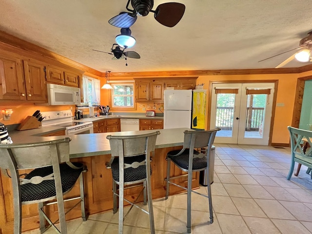 kitchen featuring french doors, a wealth of natural light, white appliances, pendant lighting, and a breakfast bar area