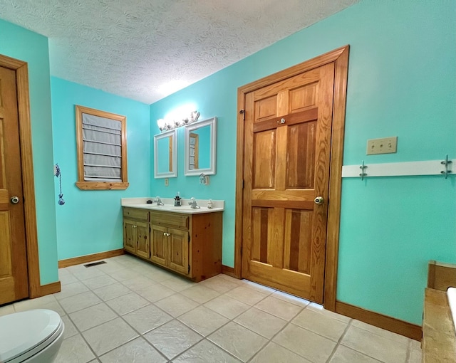 bathroom featuring vanity, toilet, and a textured ceiling