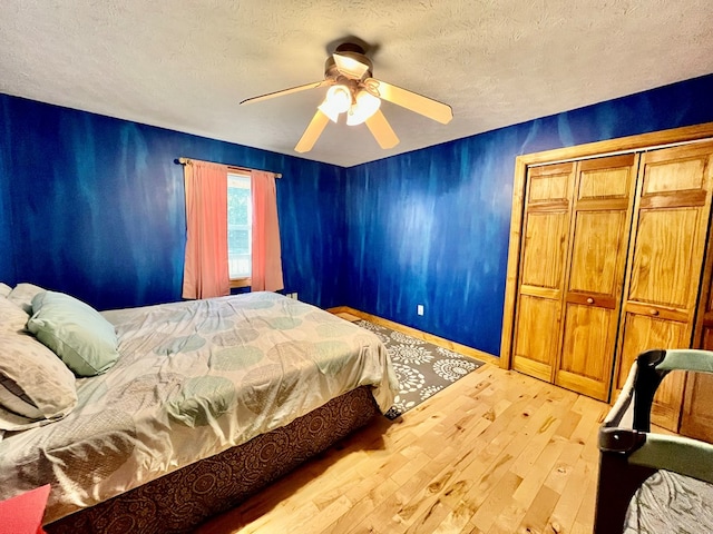 bedroom featuring a textured ceiling, ceiling fan, light hardwood / wood-style flooring, and a closet