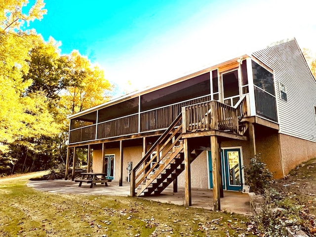 back of property featuring a patio, a deck, and a sunroom