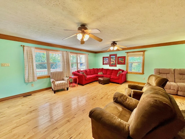 living room featuring ceiling fan, light wood-type flooring, a textured ceiling, and ornamental molding