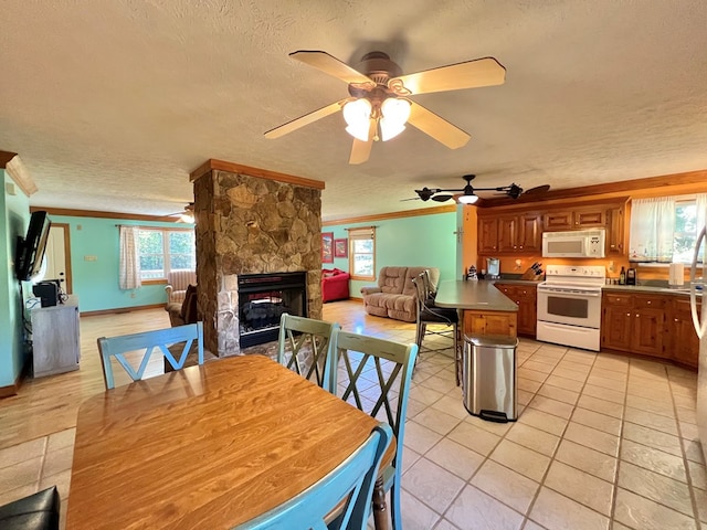 tiled dining area with a stone fireplace, crown molding, ceiling fan, and a textured ceiling