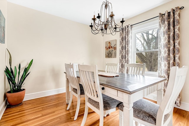 dining space with a notable chandelier, wood finished floors, and baseboards