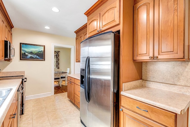 kitchen with tasteful backsplash, light countertops, appliances with stainless steel finishes, and baseboards