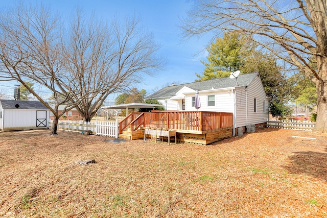 rear view of house featuring an outbuilding, a storage unit, a wooden deck, and fence