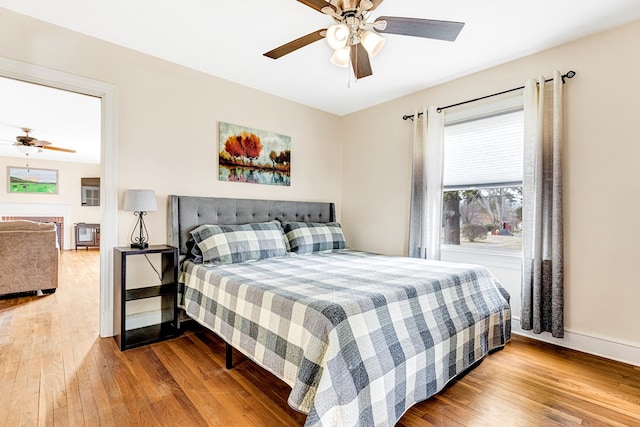 bedroom featuring wood finished floors, a ceiling fan, and baseboards