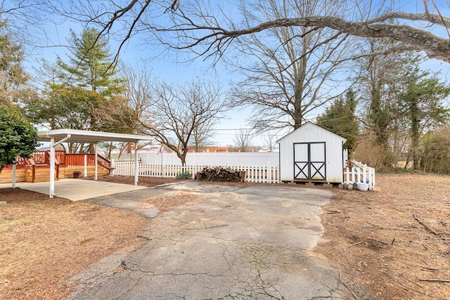 view of yard with a carport, an outbuilding, driveway, and a storage shed