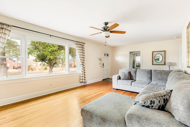 living room featuring ceiling fan, baseboards, and wood finished floors