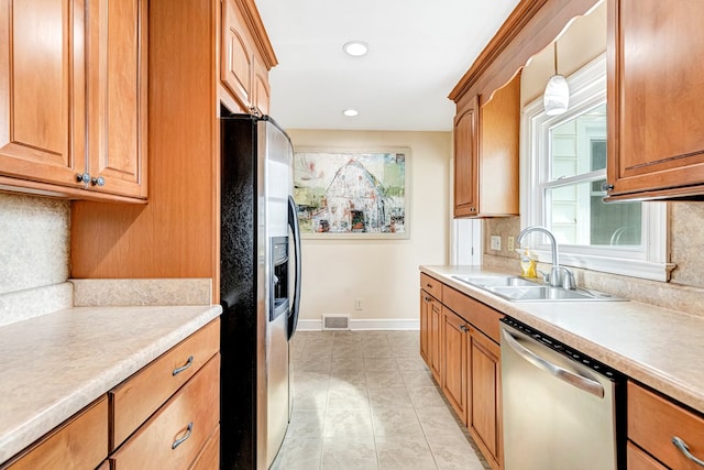 kitchen with light countertops, appliances with stainless steel finishes, hanging light fixtures, and a sink