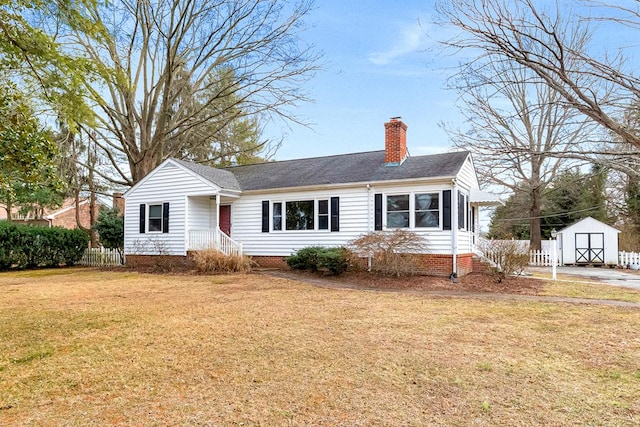 view of front of house with a chimney, a storage shed, fence, an outdoor structure, and a front lawn