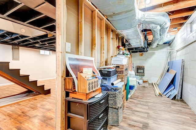 below grade area with stairs, heating unit, and wood finished floors