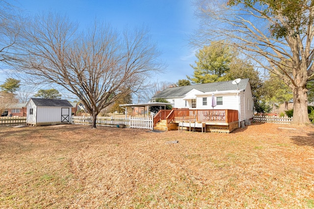 back of house featuring a storage shed, a wooden deck, a lawn, fence, and an outdoor structure