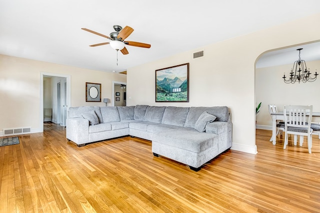 living room with ceiling fan with notable chandelier, visible vents, baseboards, and wood finished floors