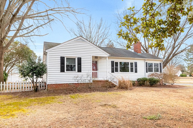 view of front of house with fence, a chimney, and a front lawn