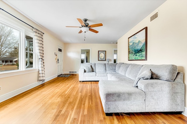 living area with baseboards, visible vents, ceiling fan, and wood finished floors