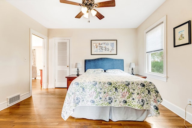 bedroom featuring baseboards, visible vents, a ceiling fan, wood finished floors, and a closet