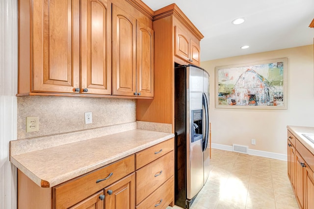 kitchen featuring baseboards, decorative backsplash, light countertops, stainless steel refrigerator with ice dispenser, and recessed lighting