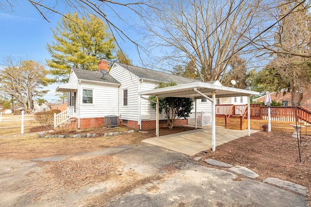 view of side of property featuring driveway, a shingled roof, a chimney, a carport, and central AC